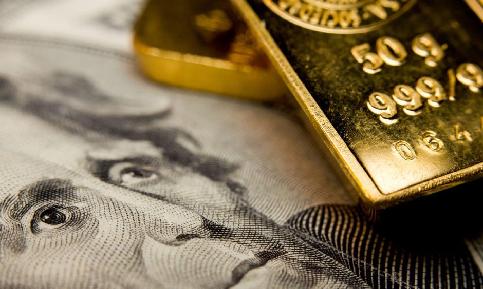 Gold bars against a dollar bill